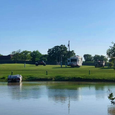 A scenic view of full hookup RV sites surrounded by lush trees, with Lake Tawakoni in the background, showcasing the peaceful lakeside atmosphere at 429 Resort & Marina in Quinlan, TX.