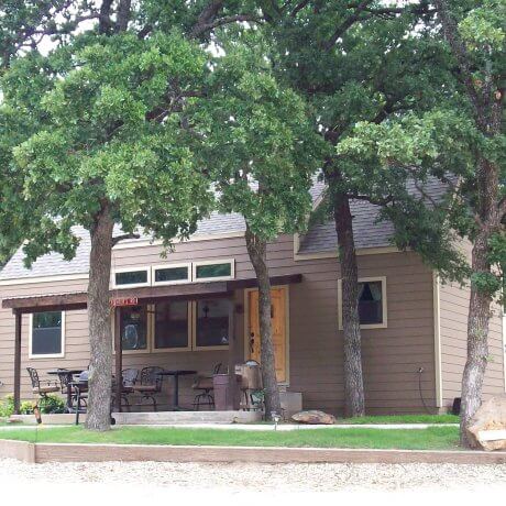 A scenic view of a cabin surrounded by lush trees, with Lake Tawakoni in the background, showcasing the peaceful lakeside atmosphere at 429 Resort & Marina in Quinlan, TX.